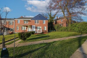 A two-story brick residential building with a front porch and a visible garage door.