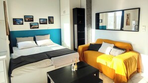 Un dormitorio moderno con cama, sofá, mesa de centro y espejo.