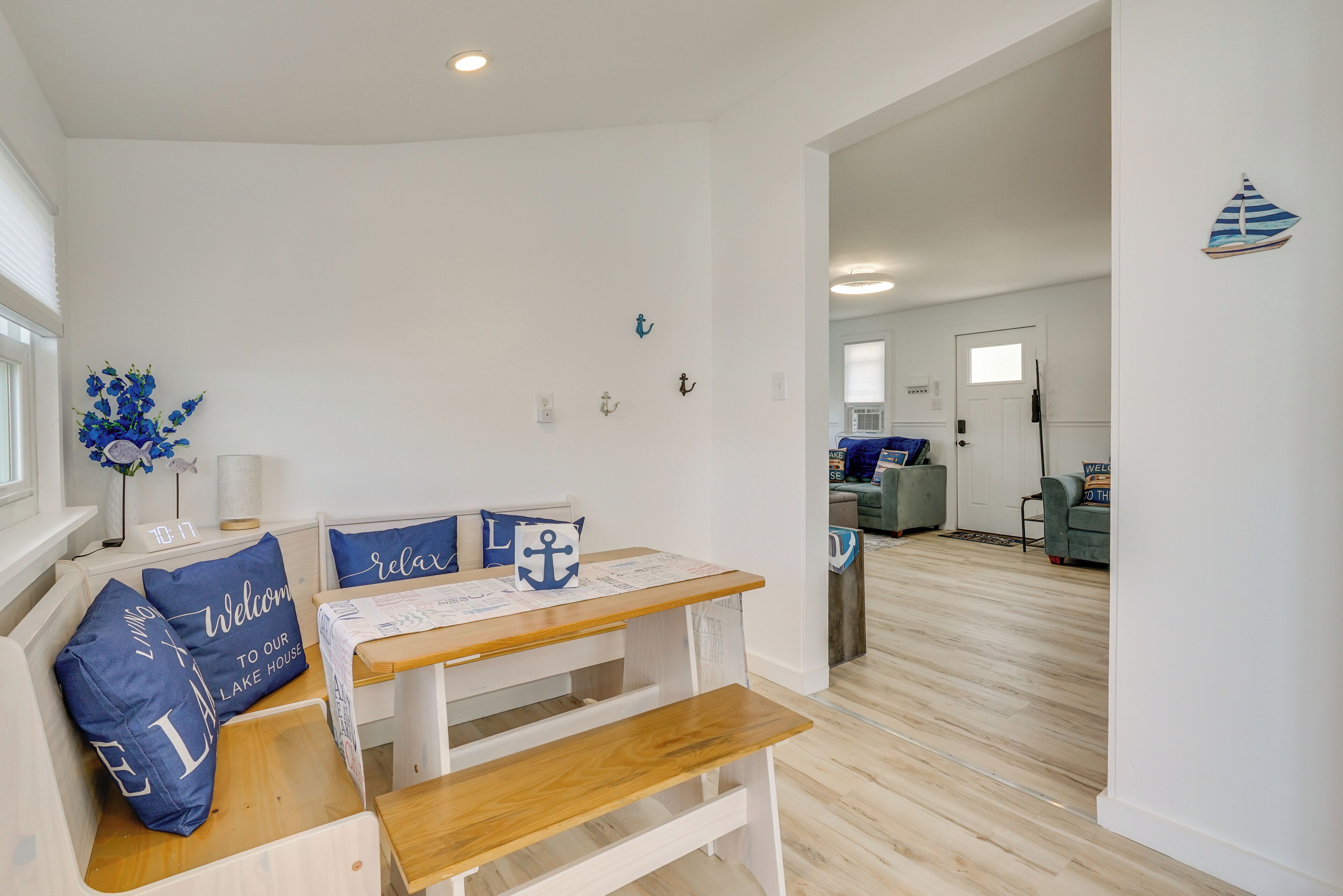 A modern living room with a wooden bench, a small table, and blue pillows with nautical themes.