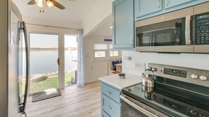 A kitchen with a view of a lake, a ceiling fan, and a kettle on the stove. - Lakefront Gem w/ Watercrafts & Dock in Coldwater! (Coldwater)