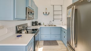 A kitchen with light blue cabinets, stainless steel appliances, and a small rug on the floor. - Lakefront Gem w/ Watercrafts & Dock in Coldwater! (Coldwater)