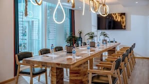 Une salle de conférence moderne, dotée d’une longue table en bois, de nombreuses chaises et d’un grand écran mural.