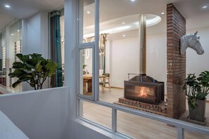 Una habitación con chimenea, comedor y escalera.