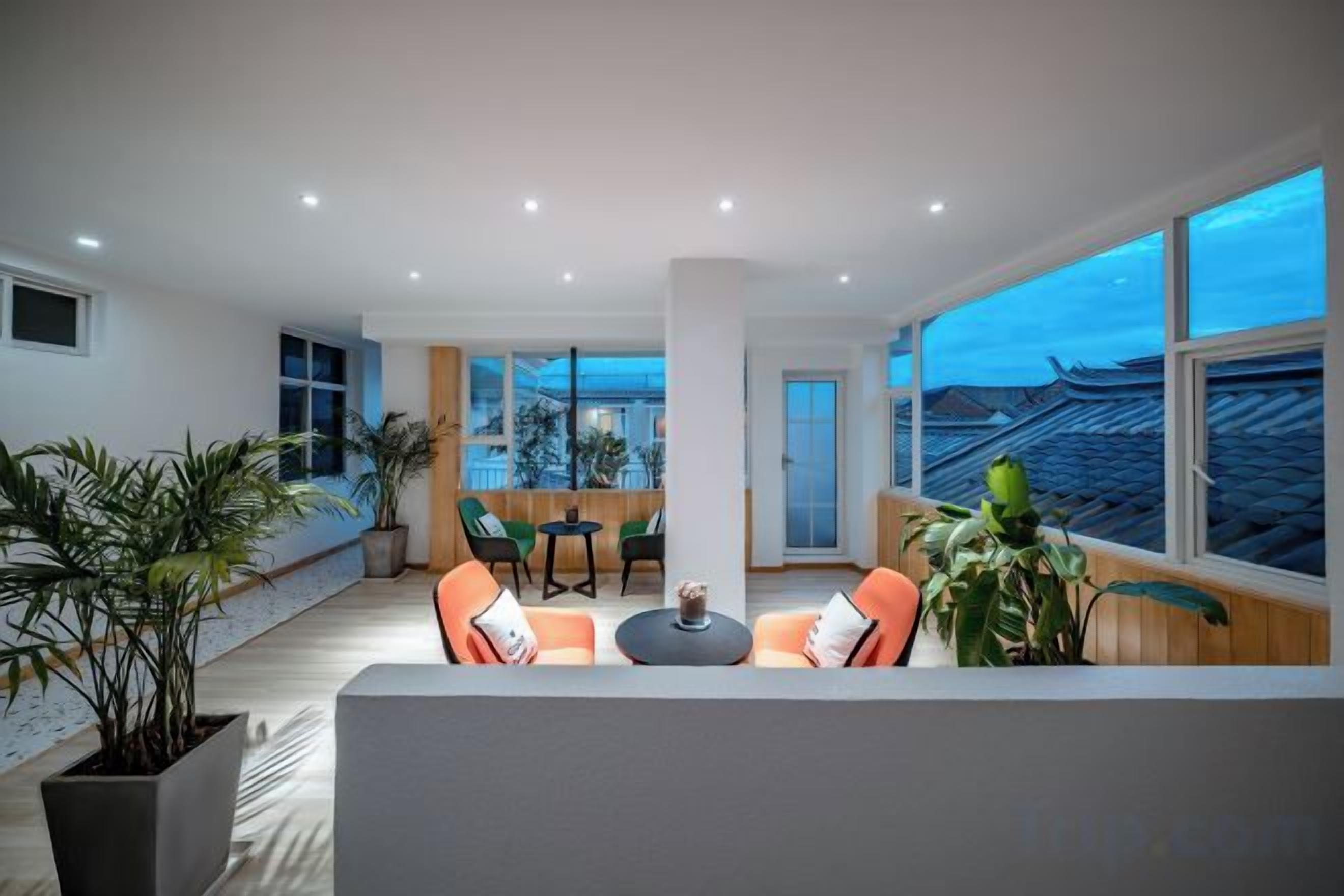 A modern interior with a seating area, large windows, and potted plants.