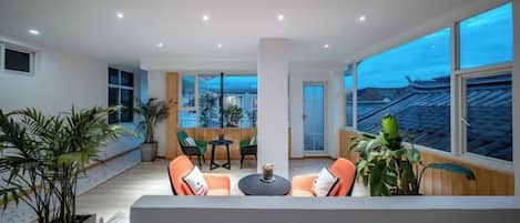 A modern interior with a seating area, large windows, and potted plants.