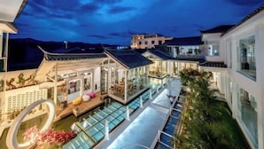 Un hôtel moderne doté d’une piscine, d’espaces de détente intérieurs et extérieurs, et présentant des éléments d’architecture traditionnels.
