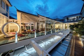 Un espace piscine extérieur moderne, doté d’un coin salon, de chaises longues et d’un chemin éclairé.
