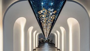 Un long couloir étroit, doté d’un plafond réfléchissant et de murs blancs.
