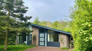 Une maison moderne avec une allée en gravier, de grandes fenêtres et une façade en briques.