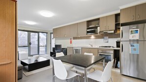 Una cucina moderna con zona pranzo, elettrodomestici in acciaio inossidabile e vista attraverso una porta scorrevole in vetro.