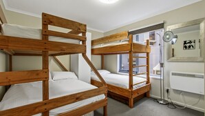 Una camera del dormitorio con letti a castello, una finestra, un termosifone e uno specchio a parete.