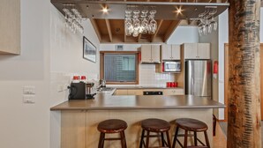 Una cocina moderna con una isla central, electrodomésticos de acero inoxidable y taburetes de madera.