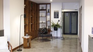 Un espace d ’accueil avec une bibliothèque en bois, un coin salon comprenant une chaise et une petite table, une plante en pot et une porte sur laquelle est apposée une pancarte indiquant qu’il s’agit d’une chambre où les animaux de compagnie sont les bienvenus.