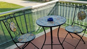 A balcony with two chairs and a table, surrounded by a green mesh fence. - Turist and pets (Sandra di Castelnuovo del Garda)