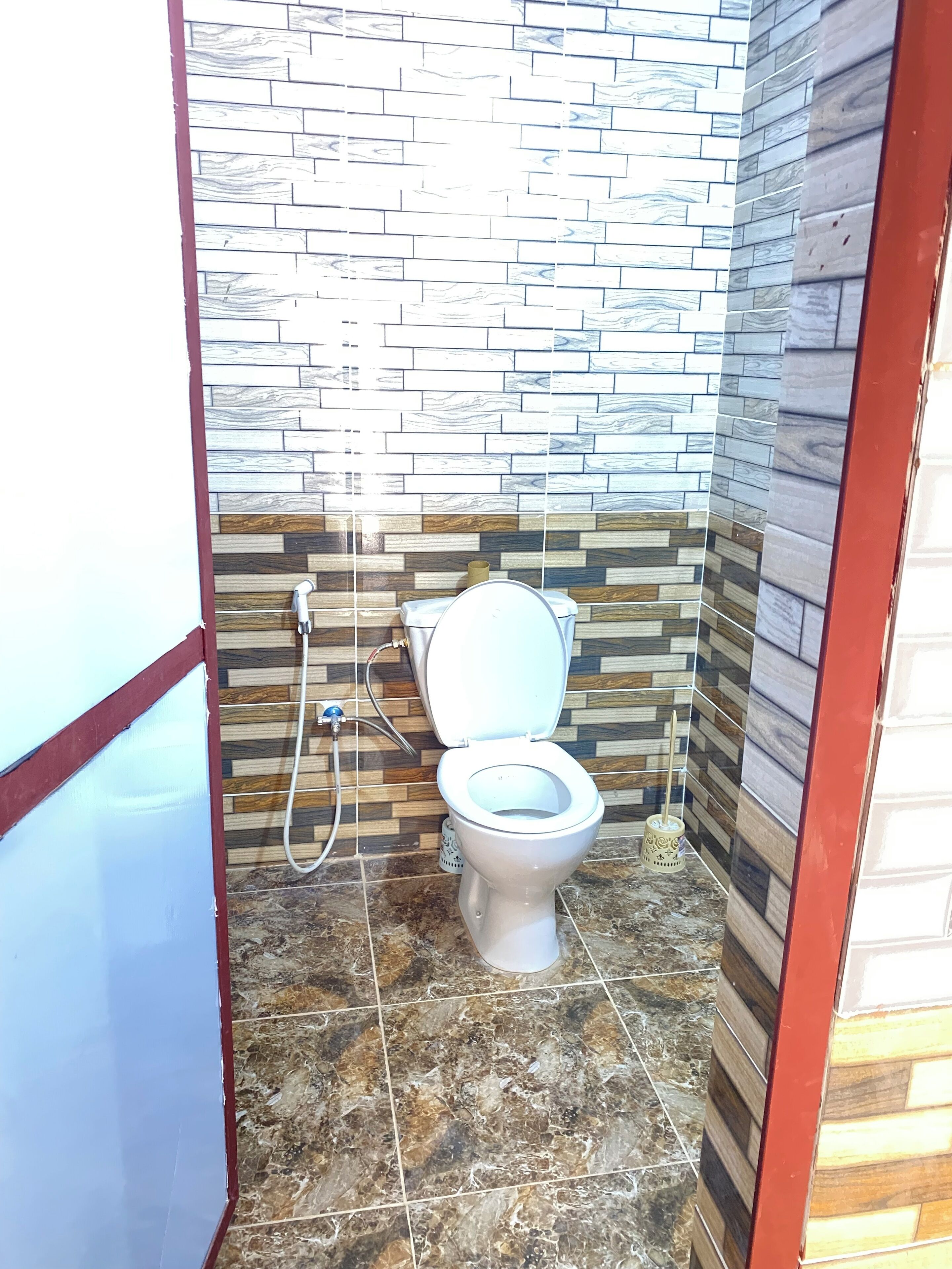 A small bathroom with a toilet, a shower, and a tiled floor.