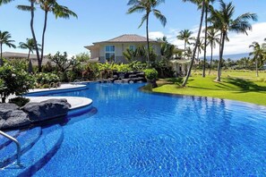 A swimming pool with a house in the background surrounded by palm trees. - Spacious 2BR+loft with Golf Views, Pool, Lanai (Waikoloa Village)