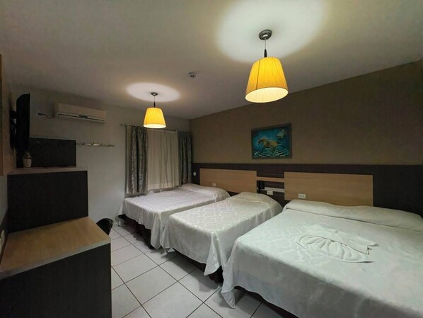 A hotel room with three beds, a flat-screen TV, an air conditioning unit, and a painting on the wall. - o recanto hotel fazenda ltda (Campo Mourão)