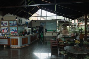 Un hall d’hôtel comprenant un comptoir d’accueil, un espace salon et une vue dégagée grâce à de grandes fenêtres.