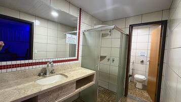 A bathroom with a sink, mirror, shower, and toilet.