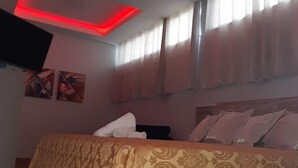 Une chambre à coucher avec un lit, un téléviseur à écran plat et un plafond doté d’un éclairage rouge.