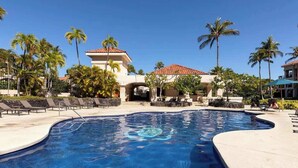 Una piscina con sillas de descanso y palmeras.