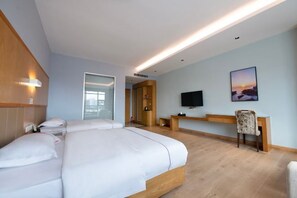 A hotel room with a bed, a desk, a chair, a TV, and a painting on the wall.