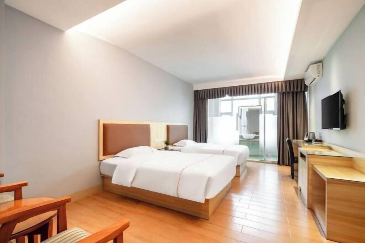 Ein Hotelzimmer mit zwei Betten, einem Schreibtisch, einem Stuhl und einem Fernseher.