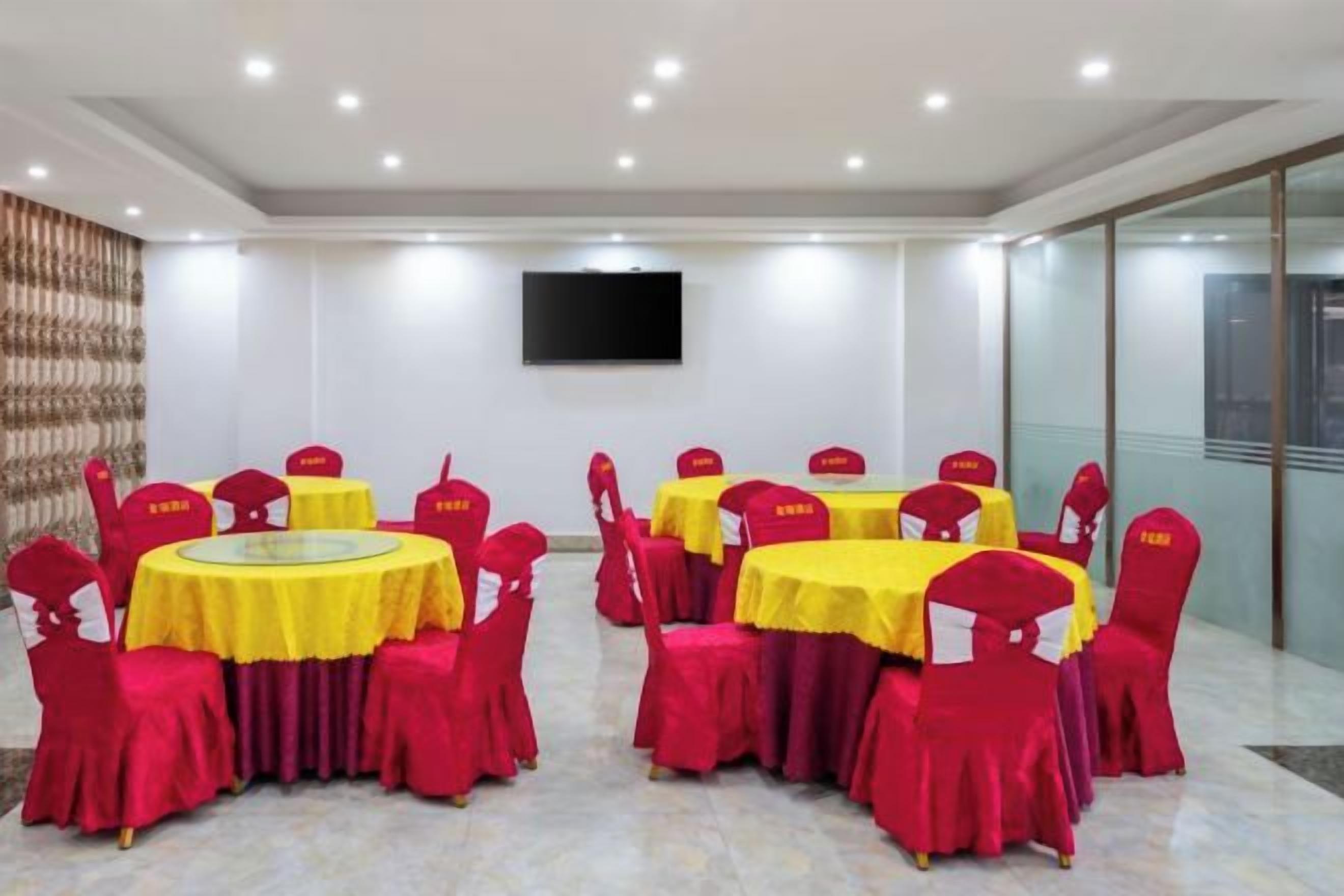 A conference room with round tables, red chairs, and a flat-screen TV on the wall.
