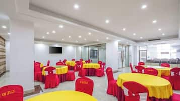 A conference room with multiple tables and chairs, a flat-screen TV mounted on the wall, and a glass partition.