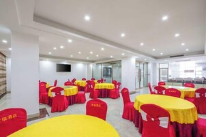 Un salón de conferencias con varias mesas y sillas, un televisor de pantalla plana en la pared y un separador de vidrio.