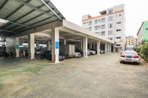 Un estacionamiento techado con varios niveles, un edificio de fachada plana y cielo despejado.