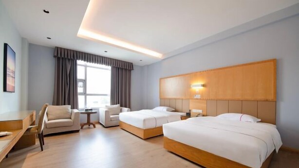 A hotel room with a large bed, a smaller bed, a desk, a chair, and a window with curtains. - Yangjiang Jinrui Business Hotel (Yangjiang)