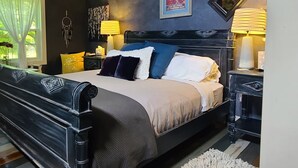 Un dormitorio con cama, mesitas de noche, ventilador de techo y ventana con cortinas.