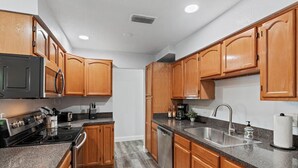 A modern kitchen with wooden cabinets, stainless steel appliances, and granite countertops.