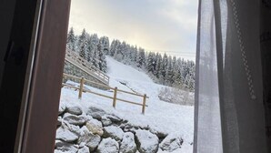 A snowy outdoor scene with a stone wall and wooden fence.