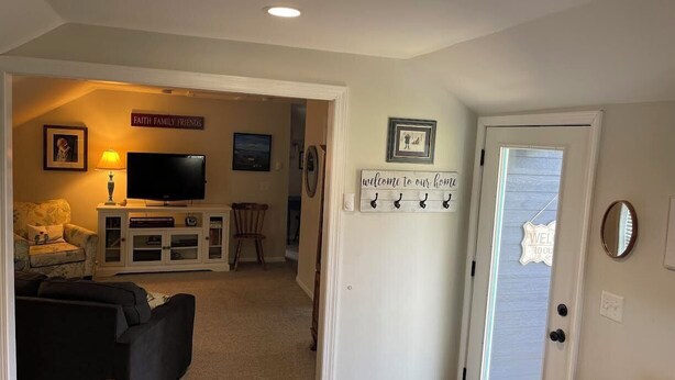 A living room with a TV, sofa, and a sign reading "FAITH FAMILY FRIENDS".