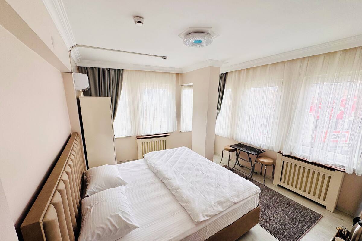 Hotellihuone, jossa on sänky, työpöytä, tuoli ja patteri.