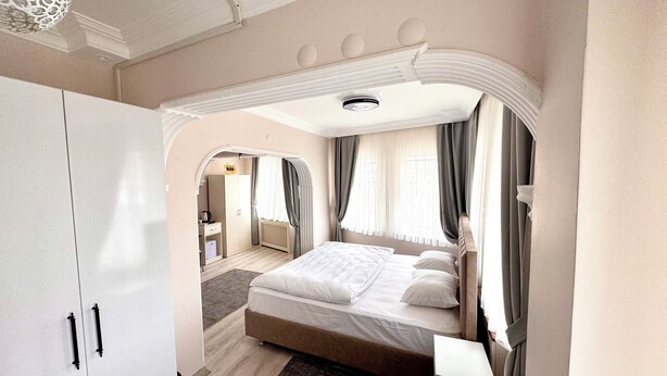 Un dormitorio amplio con una cama grande, un armario y un baño visible a través de un arco.