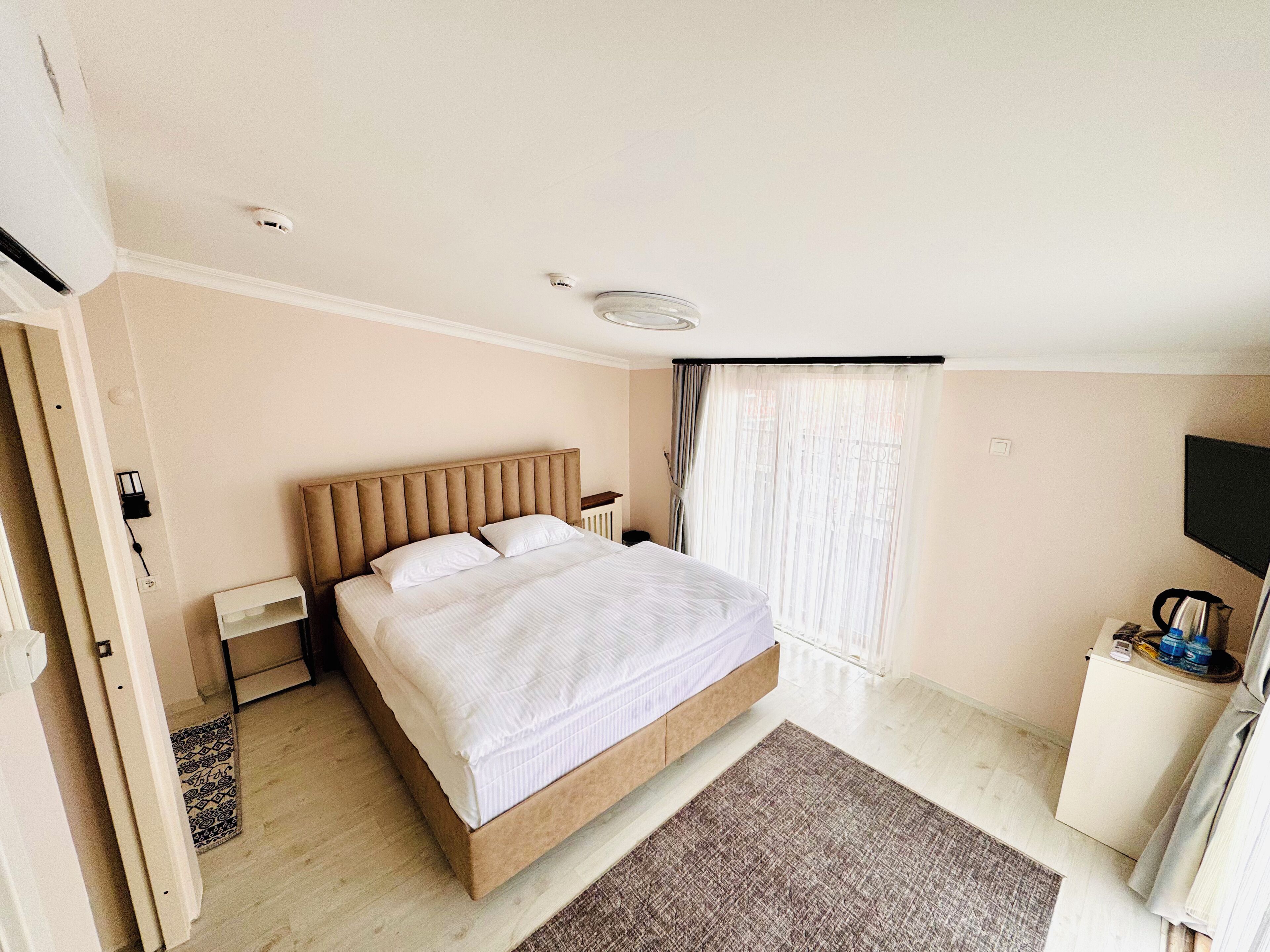 A hotel room with a bed, bedside table, and a TV.
