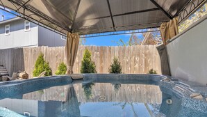 Ein klares Schwimmbecken mit Holzterrasse und überdachtem Bereich mit Metalldach.