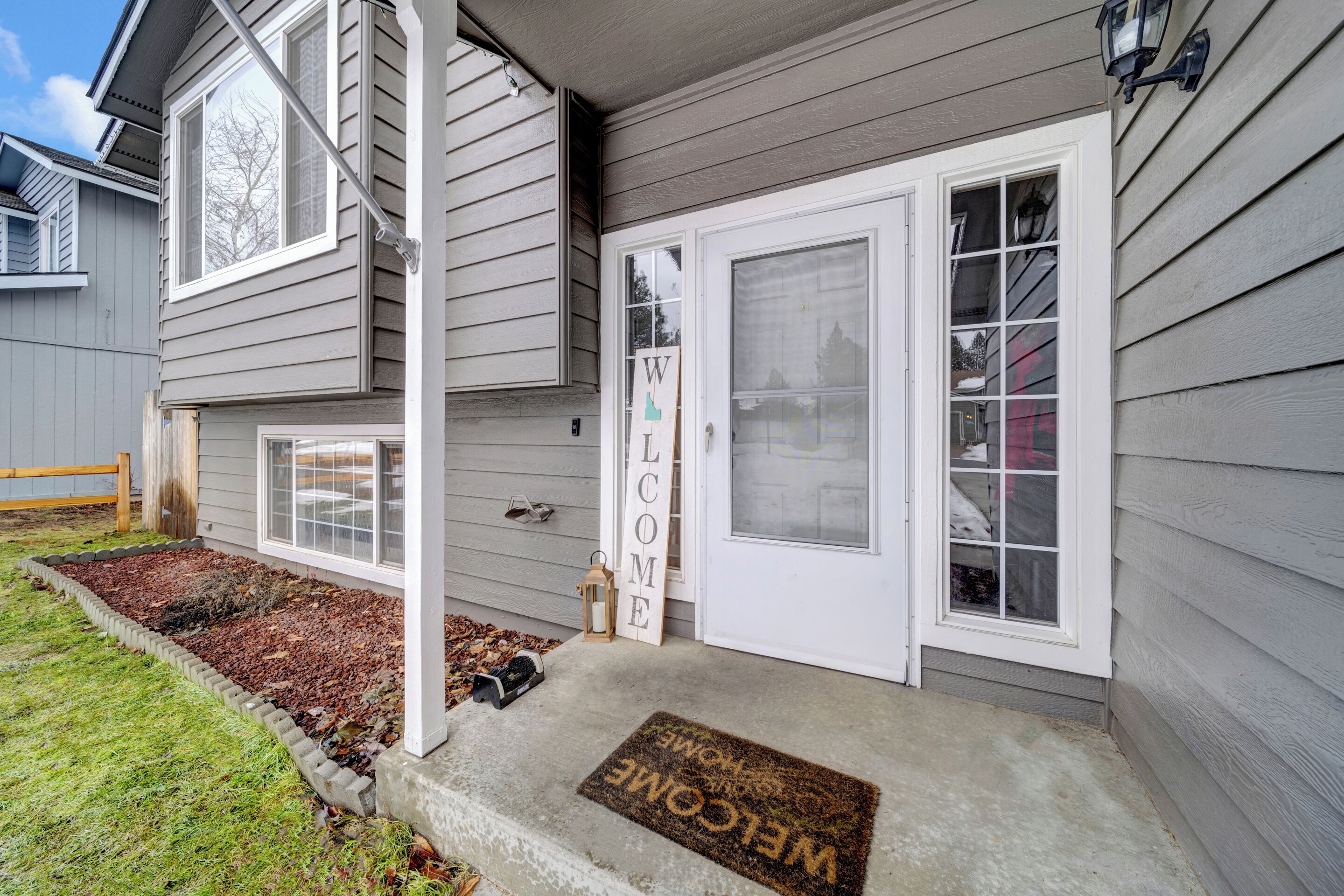 A house with a grey exterior, a white front door, and a welcome mat.