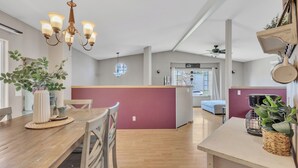 Eine moderne Küche mit Esstisch aus Holz, einer integrierten Kochinsel und Pendelleuchten.
