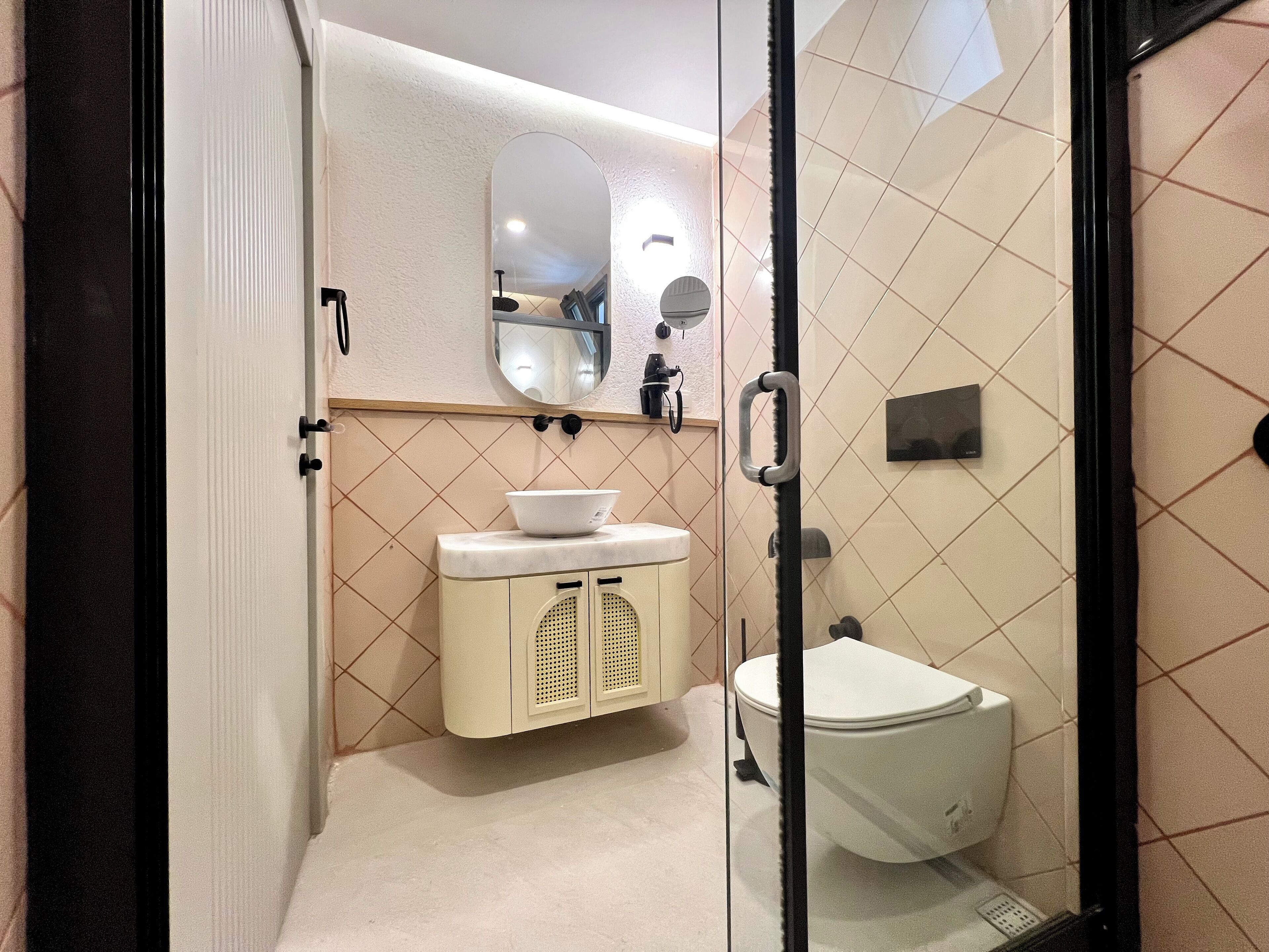 A bathroom with a toilet, sink, and mirror.