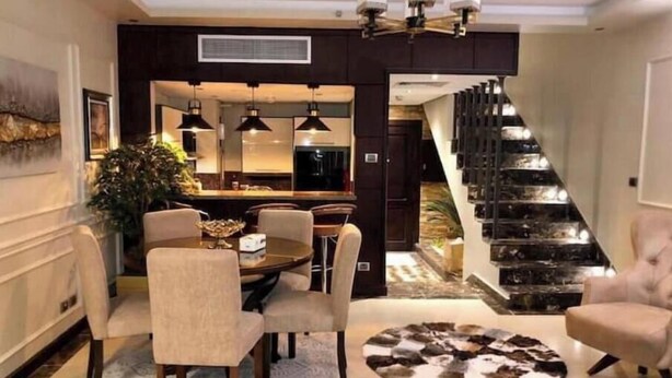 A modern dining area with a round table, chairs, and a decorative rug. - 3 bedrooms Duplex 90 st. parkmall residence (New Cairo City)