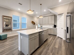 Una cocina moderna con una isla central, electrodomésticos de acero inoxidable e iluminación colgante.