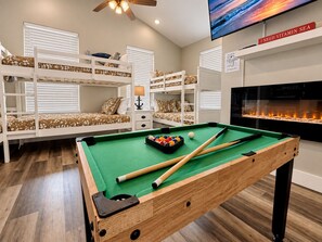 Una habitación con literas, mesa de billar y televisión.