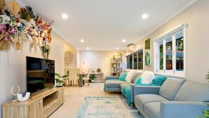 Uma sala de estar moderna com televisão, sofás, um armário de madeira e uma janela grande.
