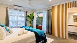 Quarto com cama, cortinas, ventilador de teto e janela.