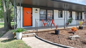 A motel with a covered porch, numbered 614, featuring outdoor seating and potted plants.