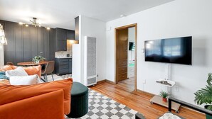 Ett modernt vardagsrum med en soffa, en tv och en matplats.